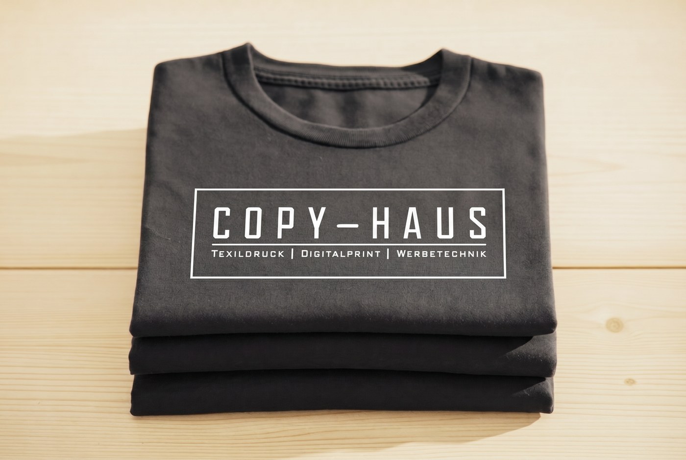 Gestapelte bedruckte T-Shirts mit Copy-Haus Logo